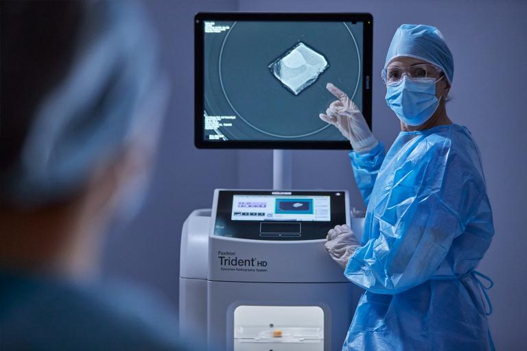 Operatore sanitario che indica il monitor e parla con una paziente