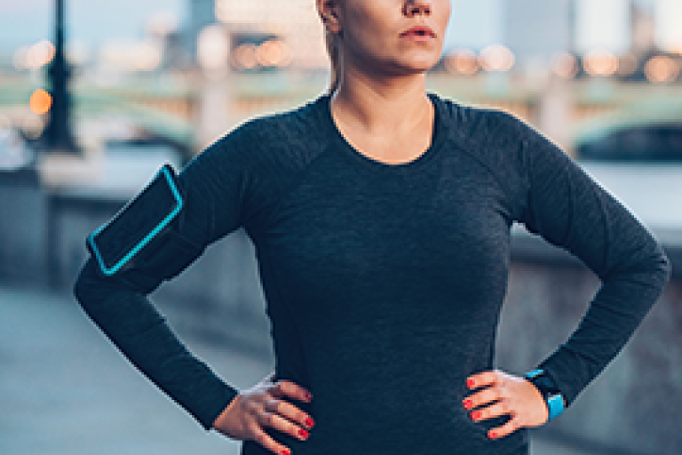 Donna in abbigliamento sportivo con le mani sui fianchi, all’aperto