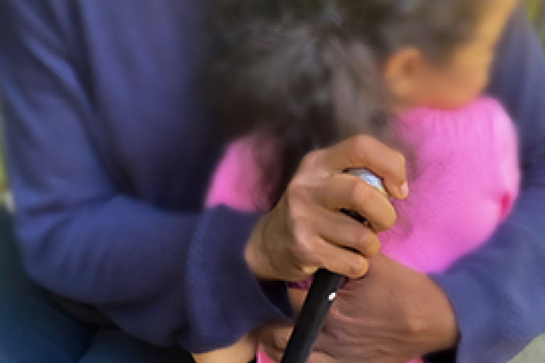 Primo piano di una donna anziana di colore che si appoggia a un bastone e abbraccia una bambina