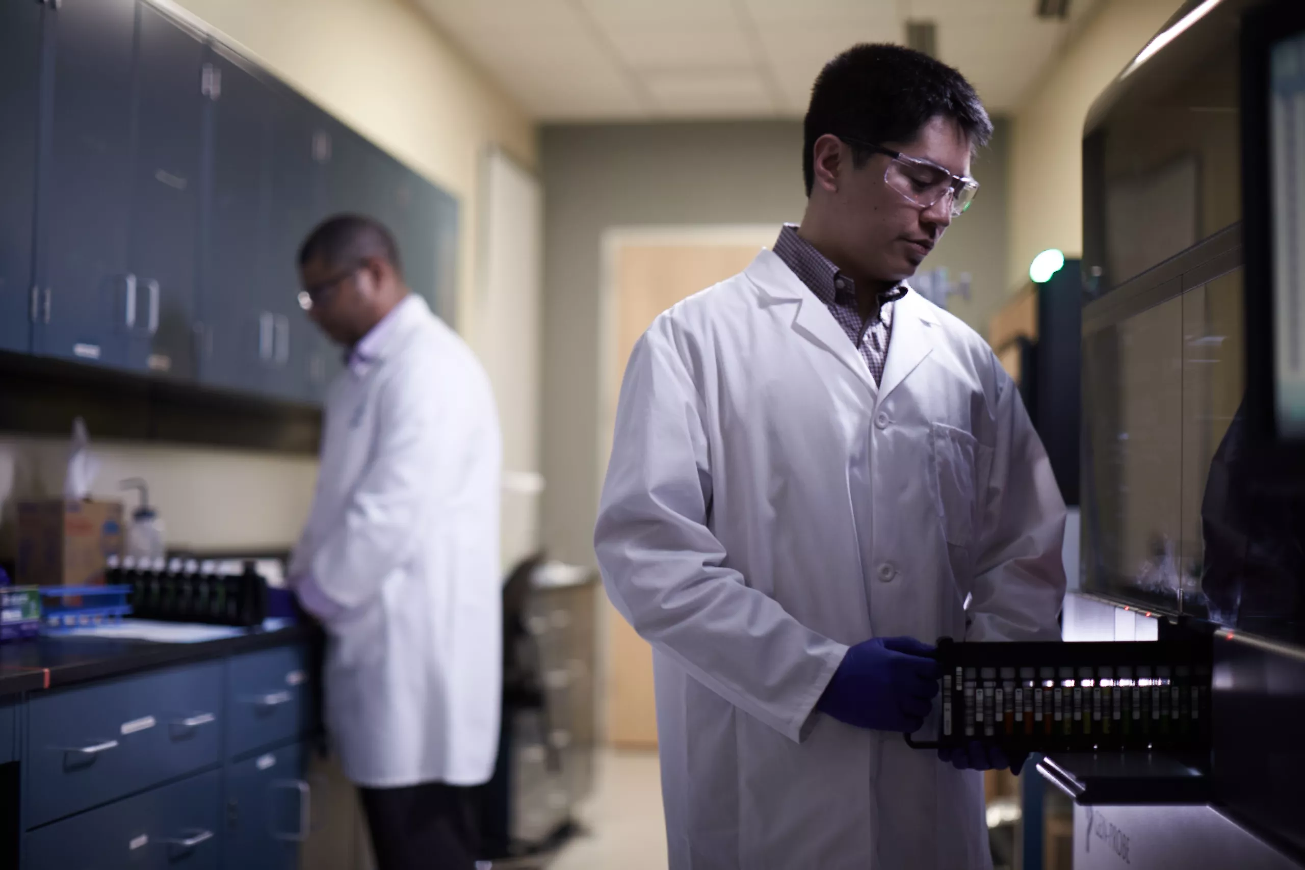 Tecnico di laboratorio che inserisce un vassoio di provette in un sistema medicale