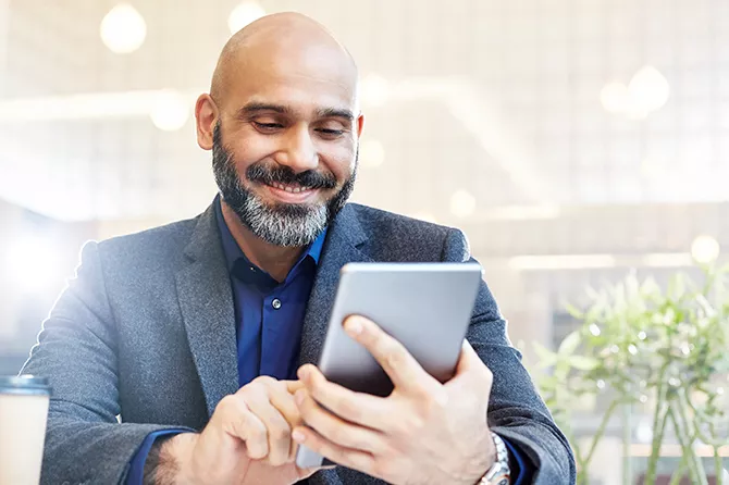 Uomo che sorride mentre interagisce con un tablet all'aperto