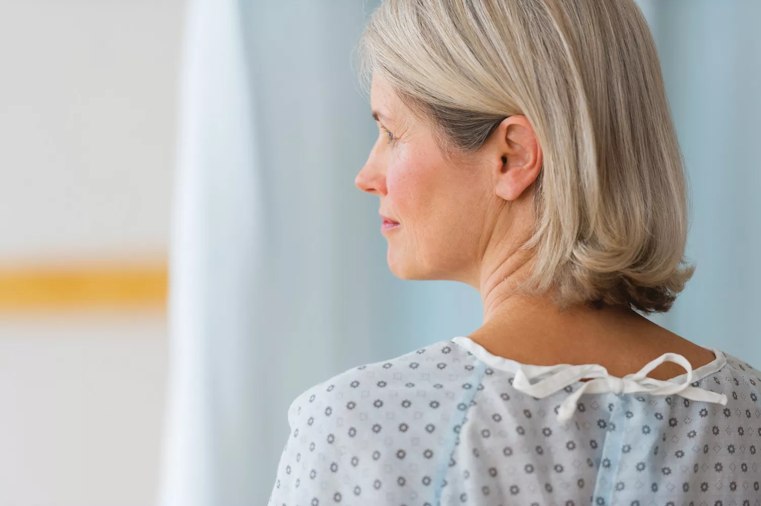 Donna anziana che guarda a sinistra con indosso un camice da ospedale